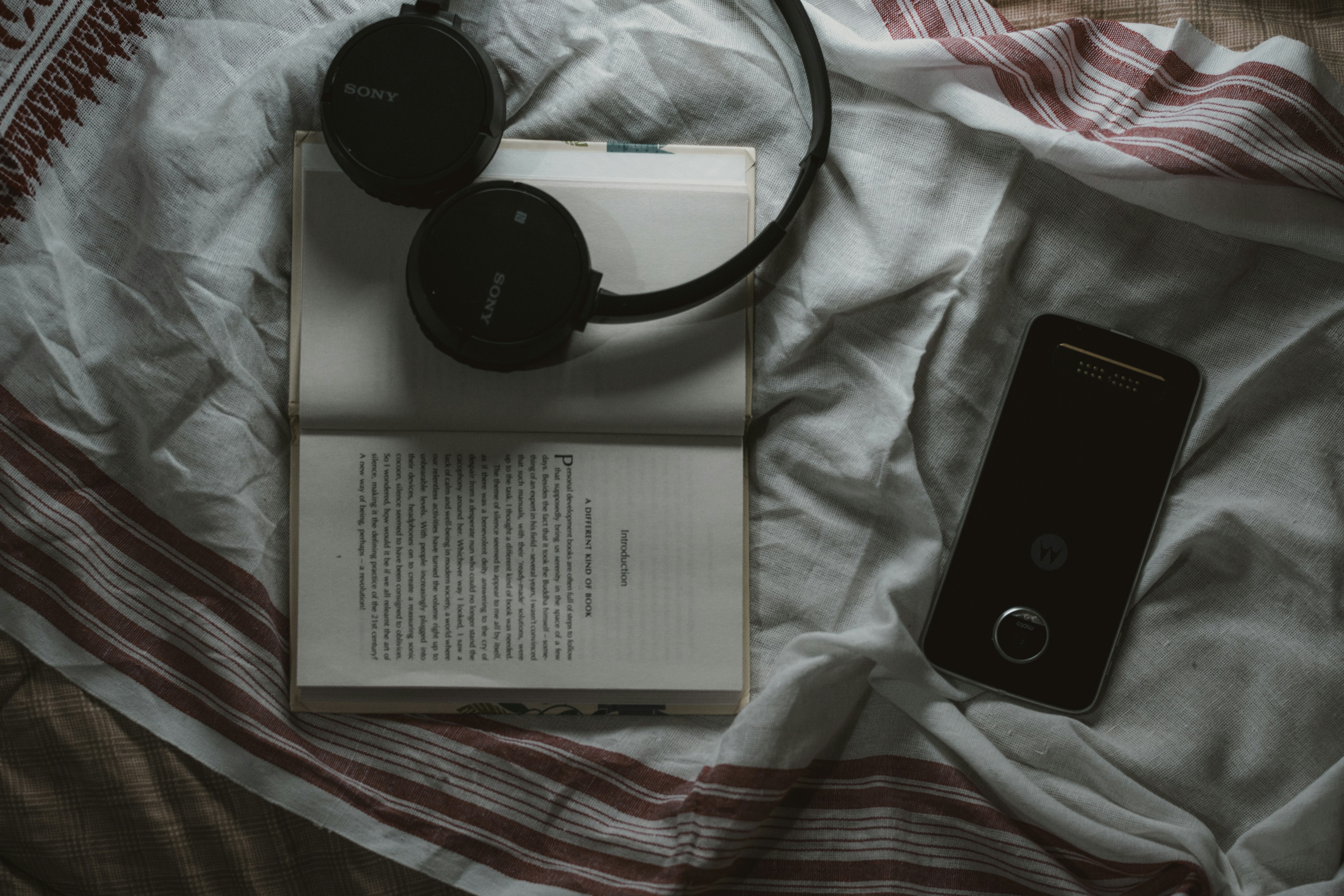 black Sony wireless headphone on top of white book